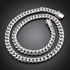 A silver-toned Cuban link chain necklace coiled on a black velvet fabric background.