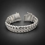A silver-toned braided cuff bracelet with a clasp closure, displayed on a rustic dark wood surface.