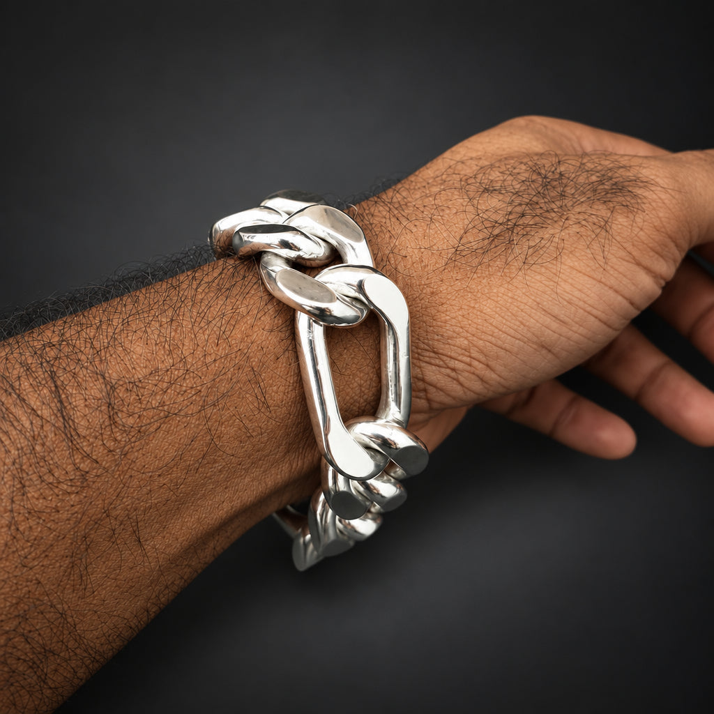 A close-up of a person's hairy wrist wearing a chunky, polished silver chain-link bracelet against a solid black background.