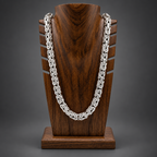 Silver chain necklace on a wooden stand with a white background