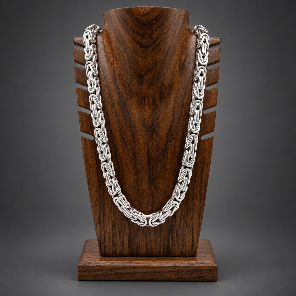 Silver chain necklace on a wooden stand with a white background