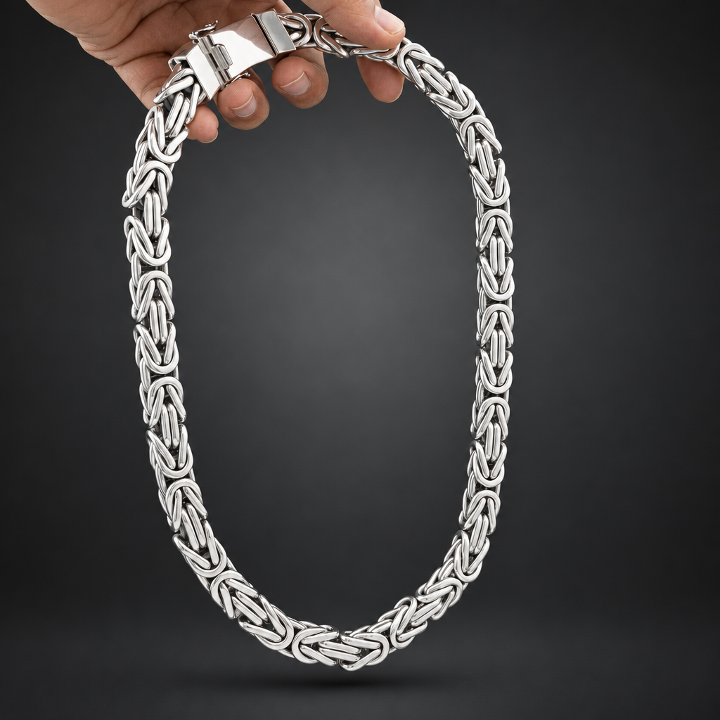 Silver chain necklace held by a hand against a black background