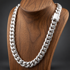 A thick silver Cuban link chain necklace displayed on a polished wooden mannequin bust against a dark gray background.