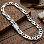 A sterling silver Cuban link chain necklace displayed on a rustic wooden surface, with a small branded box, tweezers, and a fabric pouch nearby.