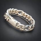 A wide, chunky silver-toned chain-link bangle bracelet in a dark background.